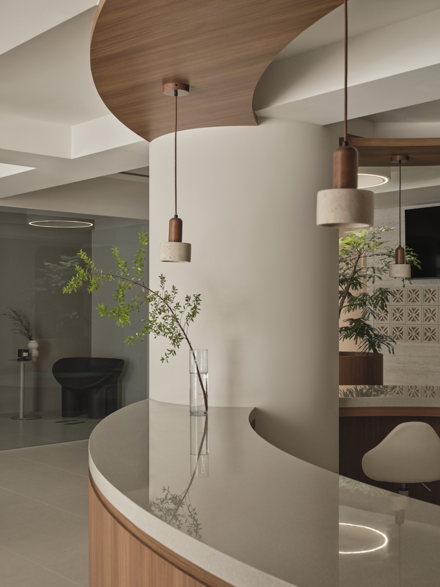 Sunmay TCM Clinic reception counter with curved wood design and greenery